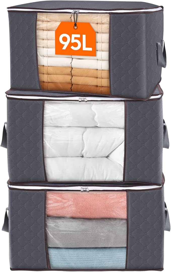 Three stacked grey Boxora storage bags with clear windows showing folded towels, a duvet and blankets